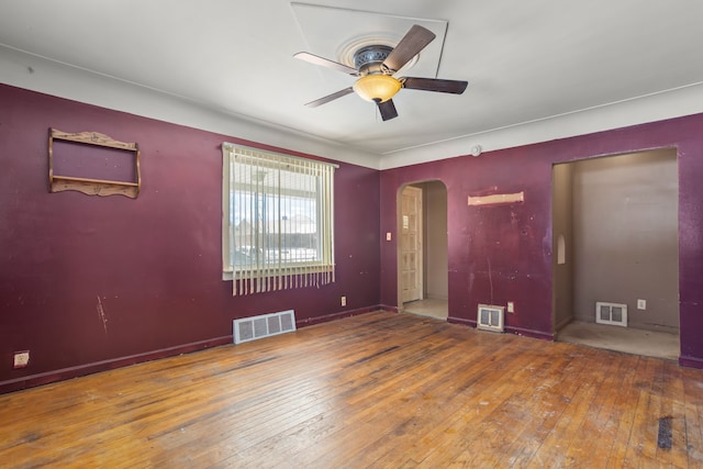 unfurnished room featuring arched walkways, visible vents, and hardwood / wood-style flooring