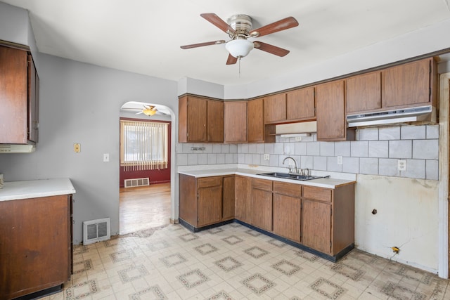 kitchen with light floors, under cabinet range hood, visible vents, and a sink