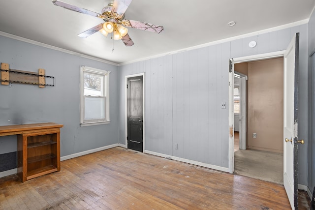 unfurnished bedroom with ornamental molding, wood-type flooring, a ceiling fan, and baseboards