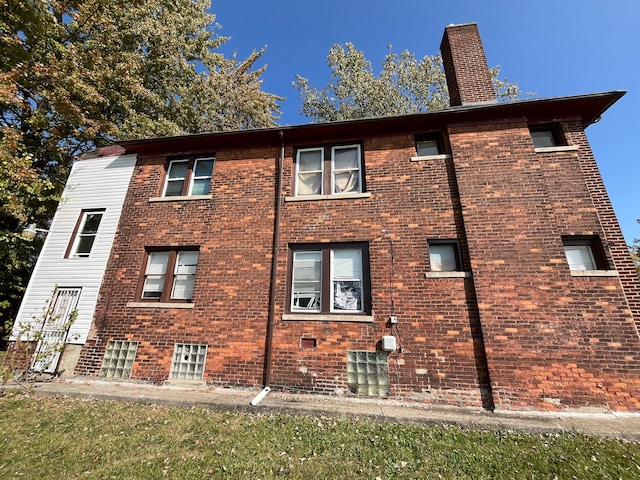 view of property exterior with brick siding and a chimney