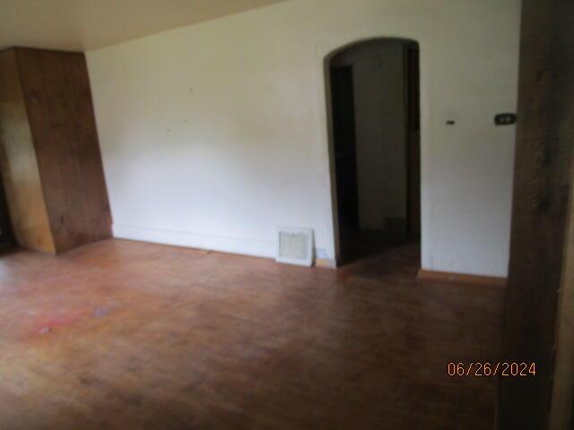 empty room featuring baseboards, visible vents, and arched walkways