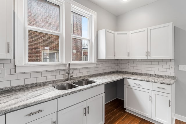 kitchen featuring dark wood finished floors, decorative backsplash, white cabinets, and a sink