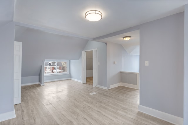 bonus room with light wood-type flooring, visible vents, vaulted ceiling, and baseboards