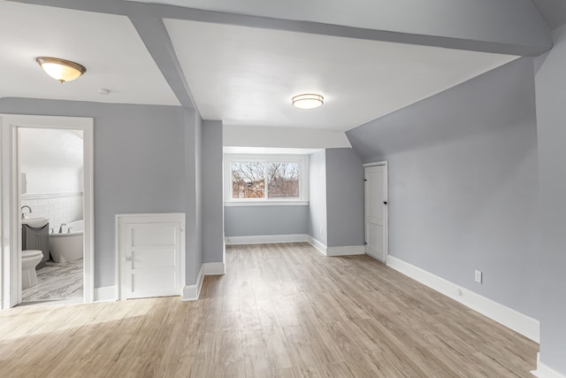 additional living space featuring lofted ceiling, light wood-style flooring, and baseboards