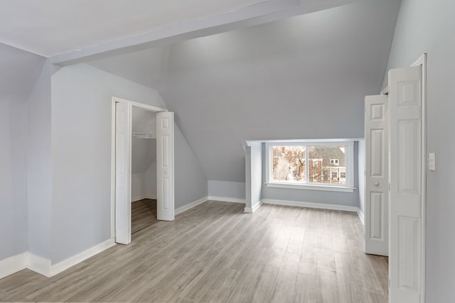 additional living space featuring light wood finished floors, baseboards, and vaulted ceiling