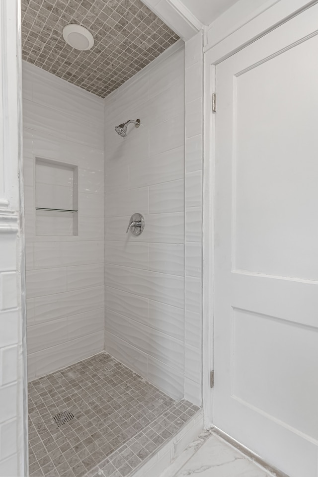 full bathroom featuring marble finish floor and a tile shower