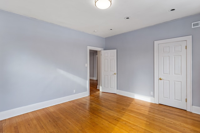 empty room with light wood-type flooring, visible vents, and baseboards