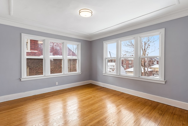 empty room featuring light wood-style floors, baseboards, and crown molding