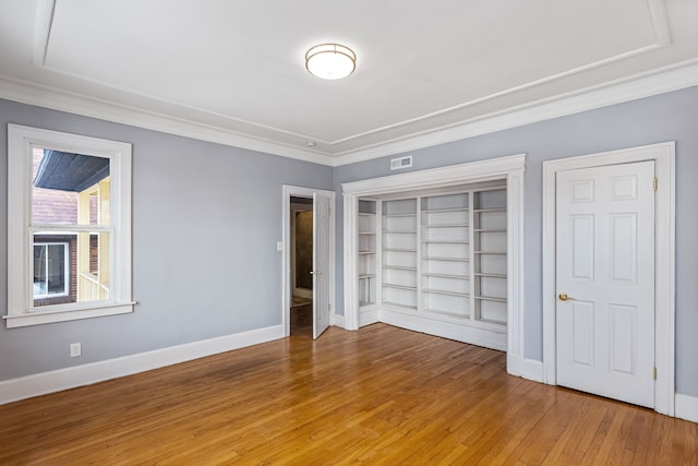 unfurnished bedroom with a closet, visible vents, light wood-style floors, ornamental molding, and baseboards