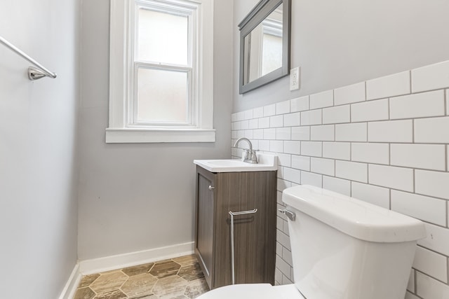 bathroom featuring a wainscoted wall, tile walls, toilet, vanity, and baseboards