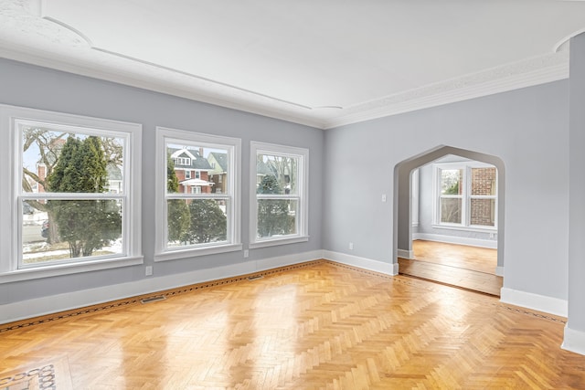 empty room with a wealth of natural light, arched walkways, and baseboards