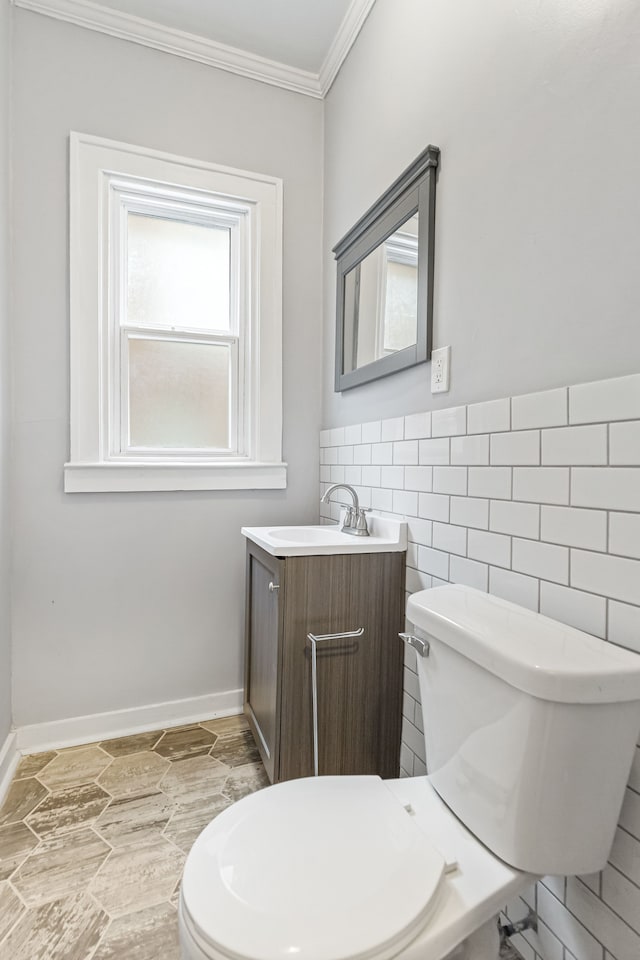 half bathroom featuring toilet, ornamental molding, tile walls, and vanity