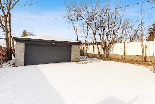 snow covered garage with a garage and fence