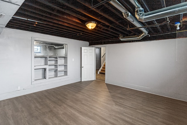 finished below grade area featuring stairs, wood finished floors, visible vents, and baseboards