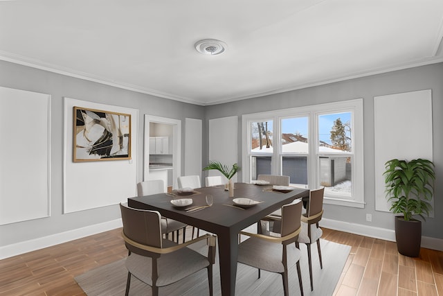 dining room featuring ornamental molding, baseboards, and wood finished floors