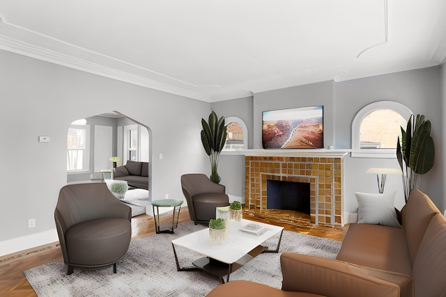 living room with plenty of natural light, arched walkways, a tiled fireplace, and ornamental molding