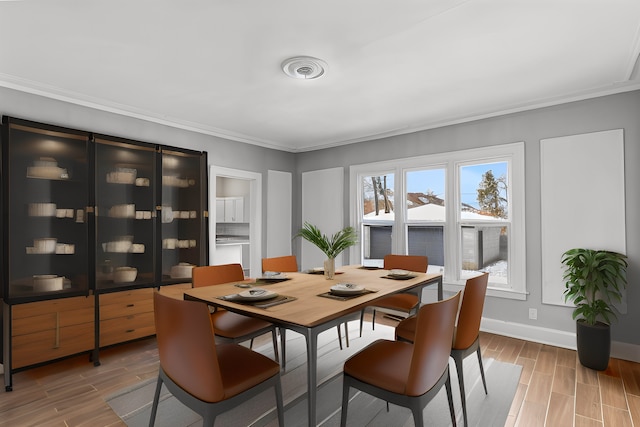 dining area with baseboards, crown molding, and wood tiled floor