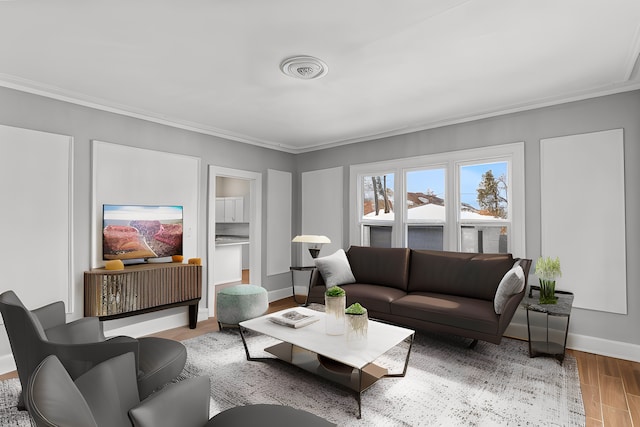 living area with ornamental molding, baseboards, visible vents, and light wood finished floors