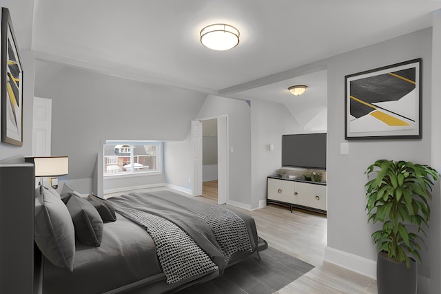 bedroom with light wood finished floors, baseboards, and vaulted ceiling