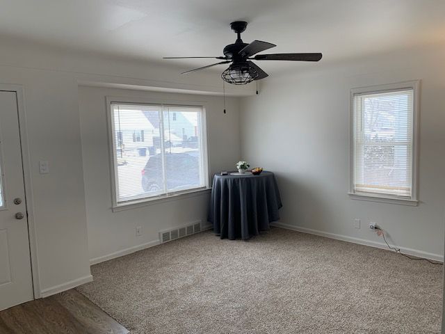 spare room with light carpet, visible vents, and baseboards