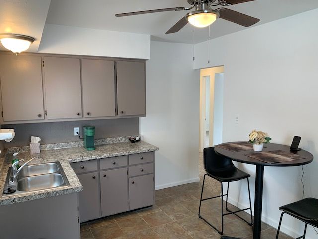 kitchen featuring ceiling fan, baseboards, gray cabinets, and a sink