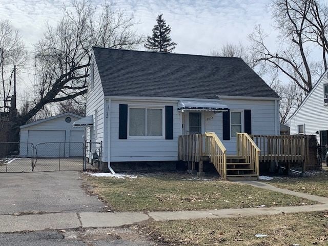 view of front of property featuring an outbuilding, roof with shingles, a gate, and a garage