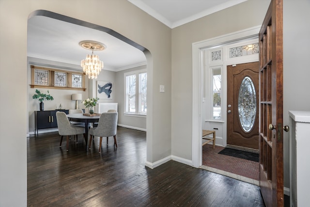 foyer featuring baseboards, arched walkways, dark wood finished floors, crown molding, and a chandelier