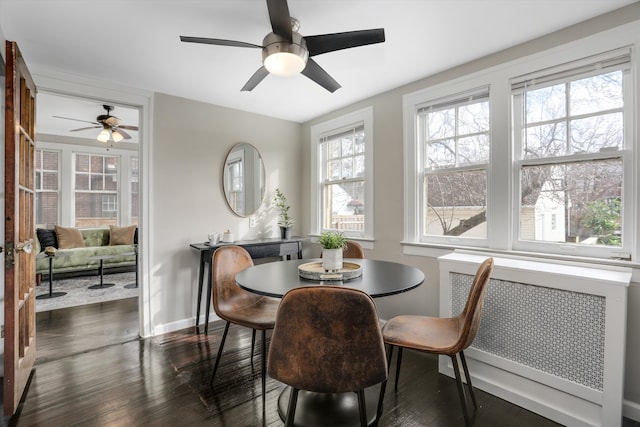 dining space featuring dark wood-style flooring, baseboards, and radiator heating unit