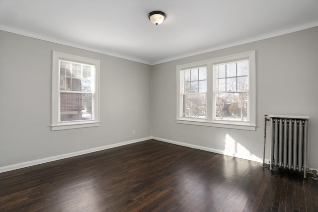 empty room featuring plenty of natural light, radiator heating unit, dark wood-style floors, and baseboards