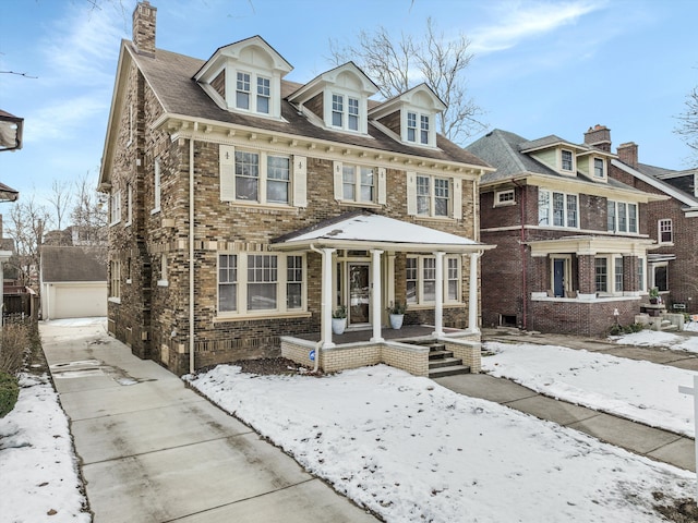 view of front of home with a detached garage, a chimney, and brick siding