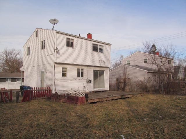 back of house featuring a wooden deck, a chimney, and a yard