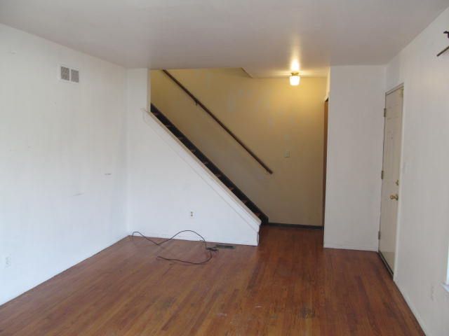 spare room featuring dark wood-style floors, stairway, and visible vents