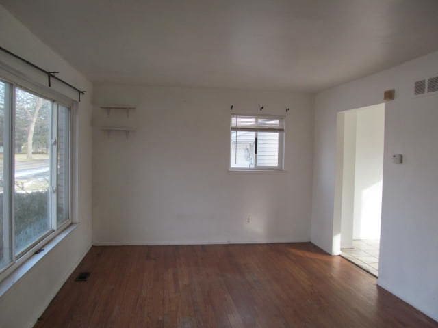 spare room with a wealth of natural light, visible vents, and dark wood-type flooring