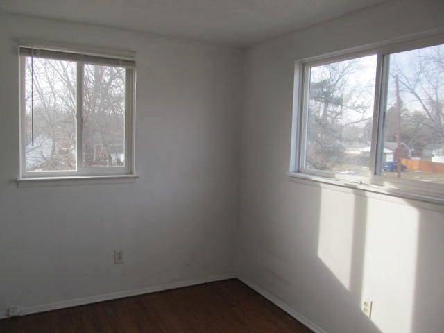 unfurnished room featuring dark wood-style floors and baseboards