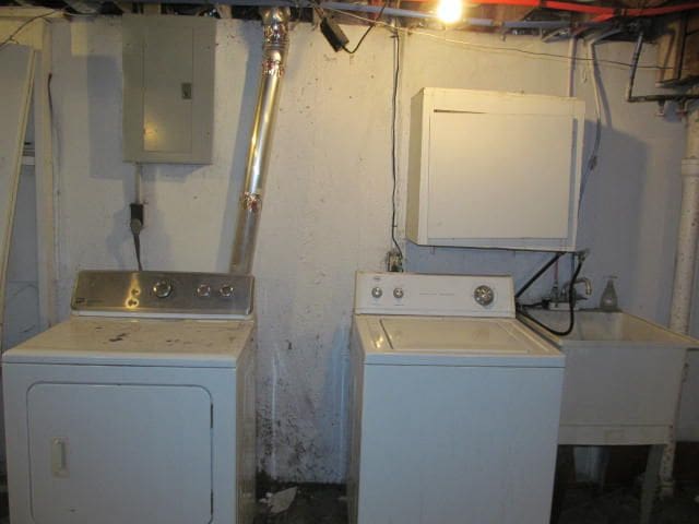 washroom with a sink, laundry area, electric panel, and washer and dryer