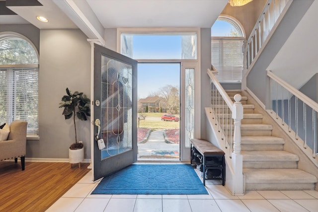 foyer featuring stairs, plenty of natural light, wood finished floors, and baseboards