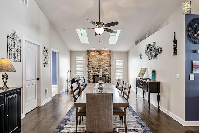 dining room with dark wood finished floors, baseboards, a ceiling fan, and vaulted ceiling with skylight