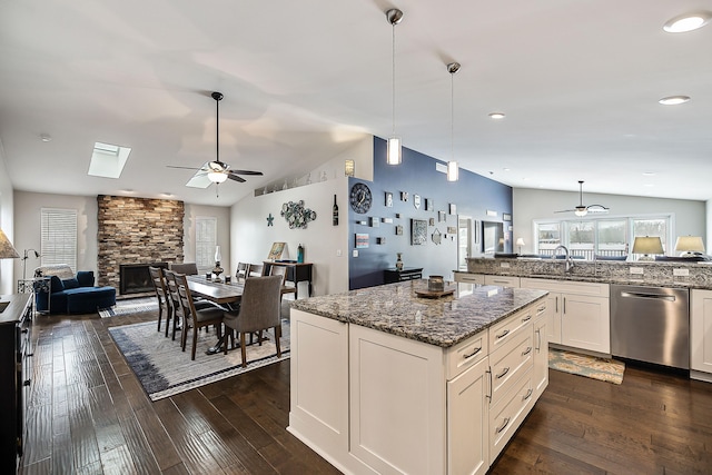 kitchen with dark stone counters, open floor plan, vaulted ceiling, pendant lighting, and stainless steel dishwasher