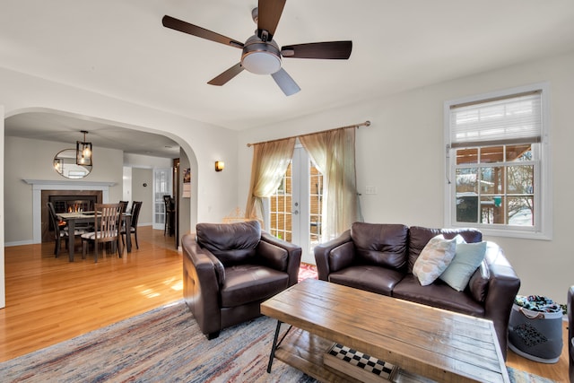 living area featuring arched walkways, french doors, wood finished floors, and a healthy amount of sunlight