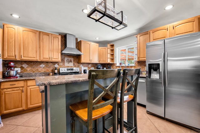 kitchen featuring light tile patterned floors, stainless steel appliances, a kitchen island, wall chimney range hood, and a kitchen bar