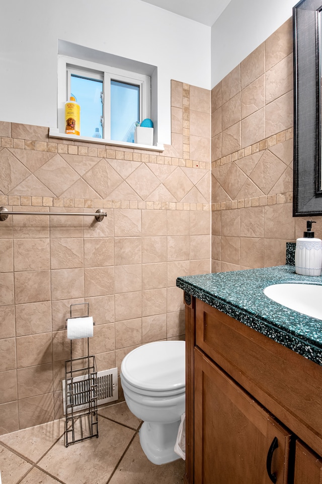 bathroom featuring toilet, vanity, visible vents, tile walls, and tile patterned floors