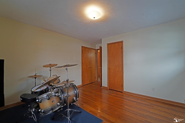 exercise room with baseboards and dark wood-type flooring