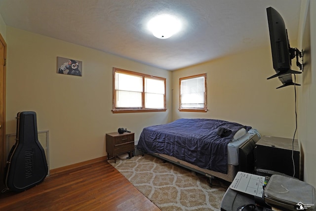 bedroom with baseboards and dark wood-type flooring