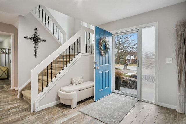 foyer entrance with stairway, baseboards, and wood tiled floor