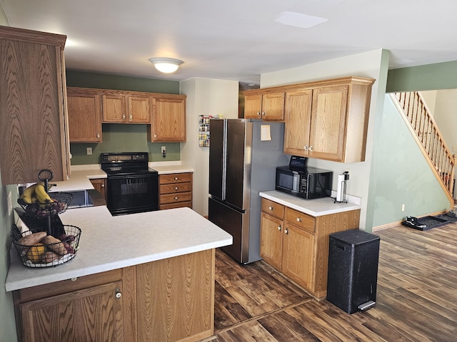 kitchen featuring dark wood-style flooring, baseboards, light countertops, black appliances, and brown cabinetry