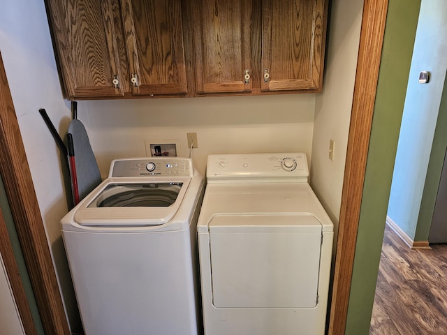 laundry room with washing machine and dryer, dark wood-style flooring, and cabinet space