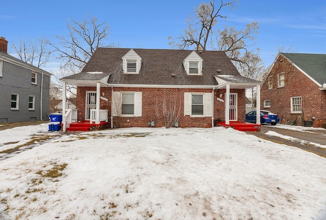 view of front of property with brick siding and roof with shingles