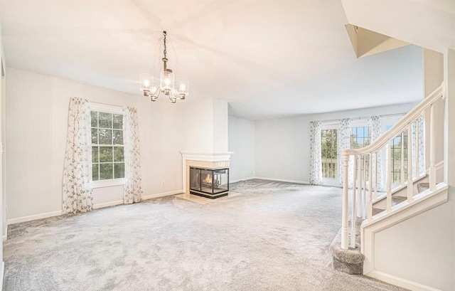 unfurnished living room featuring carpet floors, baseboards, a multi sided fireplace, and stairs