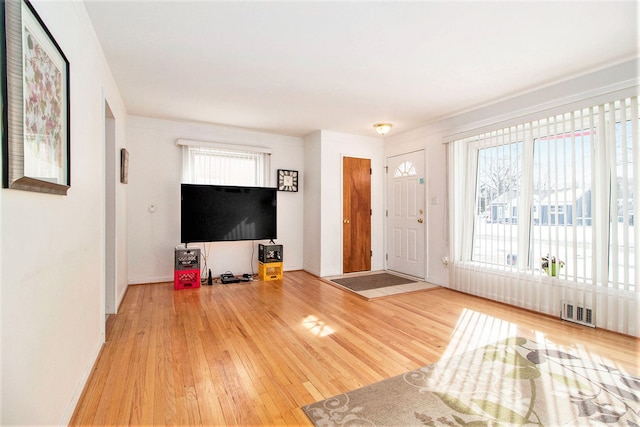 unfurnished living room featuring wood finished floors, visible vents, and baseboards