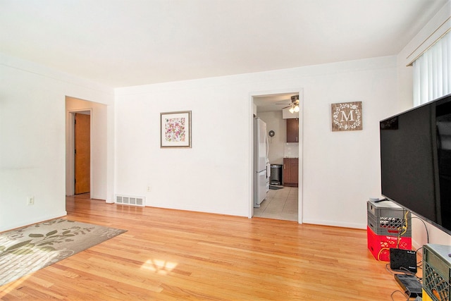 living room with a ceiling fan, light wood-type flooring, visible vents, and baseboards